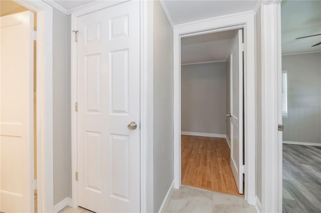 corridor featuring light wood-type flooring, crown molding, and baseboards