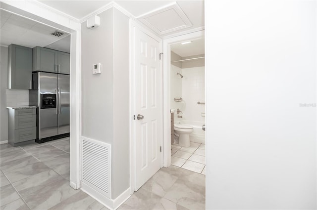 full bath with marble look tile flooring, bathing tub / shower combination, toilet, and baseboards