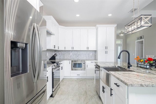 kitchen with stainless steel appliances, a sink, a center island with sink, tasteful backsplash, and white cabinets