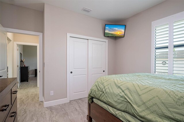 bedroom with a closet, baseboards, and light marble finish flooring