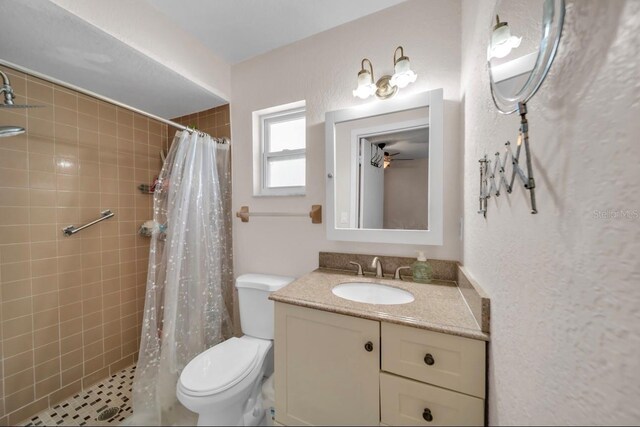 bathroom with toilet, tiled shower, and vanity