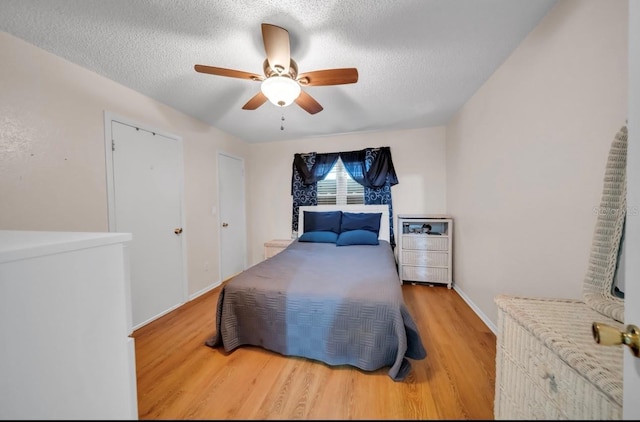 bedroom with wood finished floors, a textured ceiling, ceiling fan, and baseboards