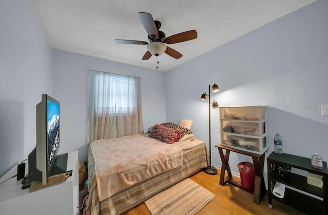 bedroom with light wood finished floors, a textured ceiling, a ceiling fan, and baseboards