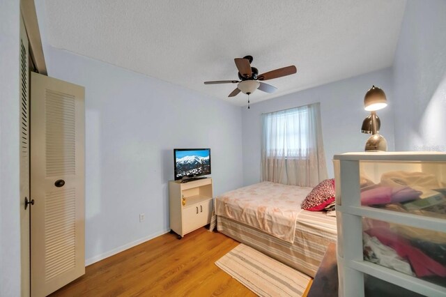 bedroom with light wood finished floors, baseboards, and ceiling fan