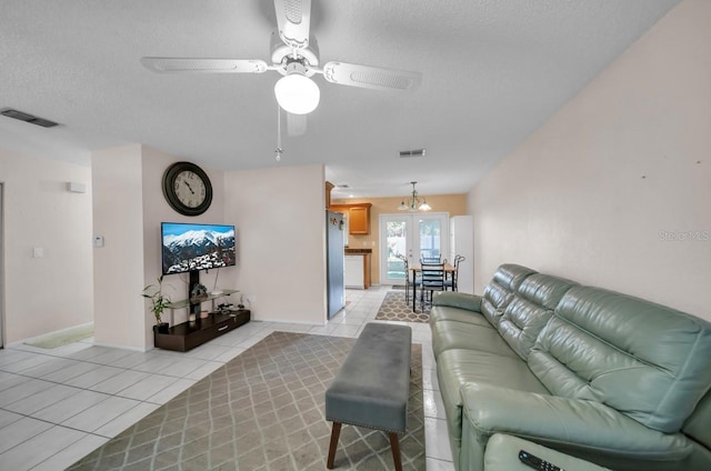 living area with light tile patterned floors, a textured ceiling, a ceiling fan, and baseboards