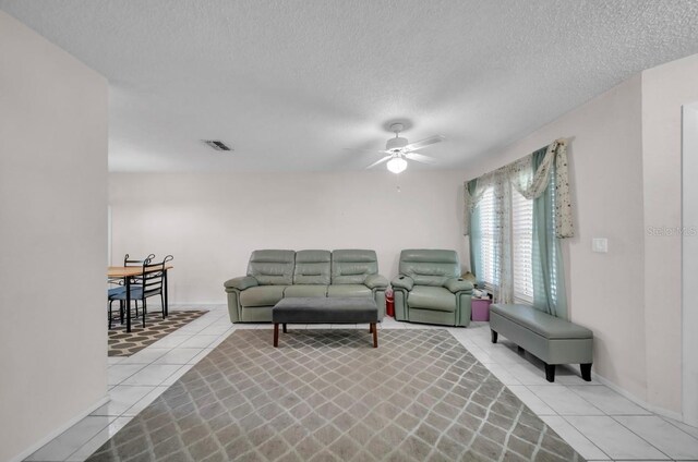 living room with light tile patterned floors, a ceiling fan, and a textured ceiling