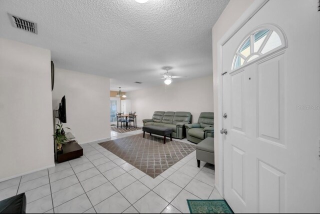 foyer entrance with ceiling fan, a textured ceiling, plenty of natural light, and light tile patterned flooring