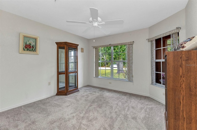 carpeted spare room with a ceiling fan and baseboards