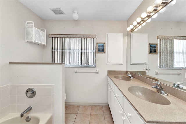 bathroom with a bath, tile patterned flooring, baseboards, double vanity, and toilet