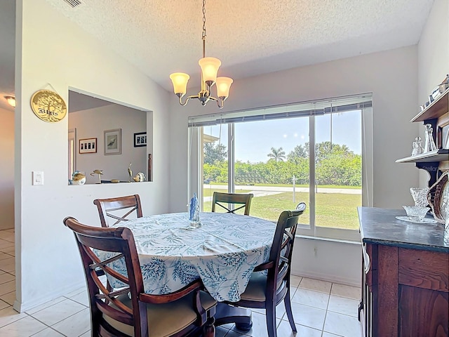 dining area with a textured ceiling, healthy amount of natural light, a chandelier, and light tile patterned floors