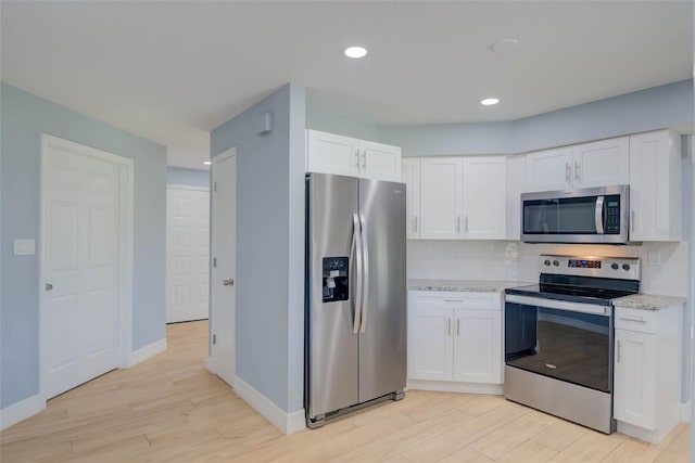 27050 Pelotas Dr, Punta Gorda, FL 33983 - kitchen featuring stainless steel appliances, light wood-style floors, white cabinetry, baseboards, and light stone countertops