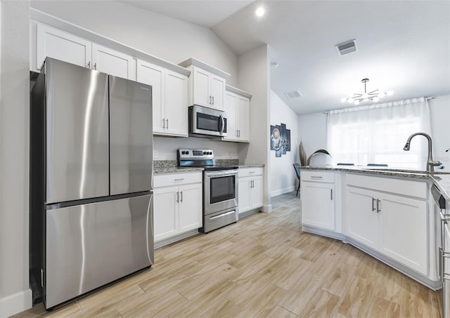 7664 Meroni Blvd, North Port, FL 34291 - kitchen with stainless steel appliances, vaulted ceiling, a sink, baseboards, and white cabinets