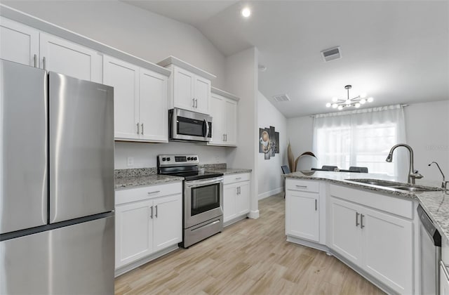 7664 Meroni Blvd, North Port, FL 34291 - kitchen with stainless steel appliances, a sink, vaulted ceiling, white cabinets, and a chandelier