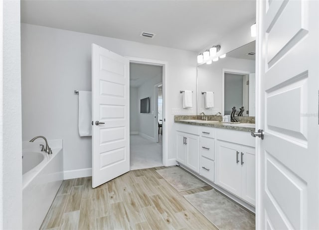 7664 Meroni Blvd, North Port, FL 34291 - full bathroom featuring wood finished floors, double vanity, a bath, and baseboards