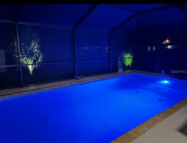 7664 Meroni Blvd, North Port, FL 34291 - pool at night with glass enclosure and an outdoor pool