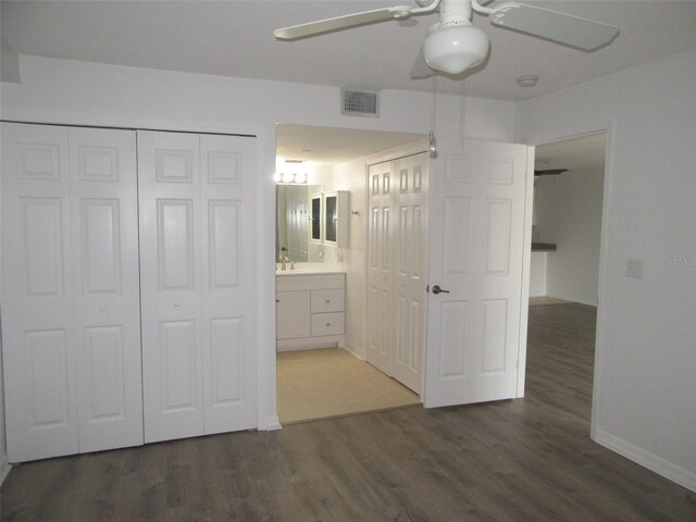 150 Harborside Ave Unit 124, Punta Gorda, FL 33950 - unfurnished bedroom featuring wood finished floors, ensuite bathroom, baseboards, and a ceiling fan