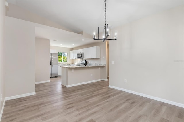 2381 Sheila Ln, North Port, FL 34286 - kitchen featuring stainless steel appliances, a chandelier, open floor plan, a peninsula, and light wood-style flooring