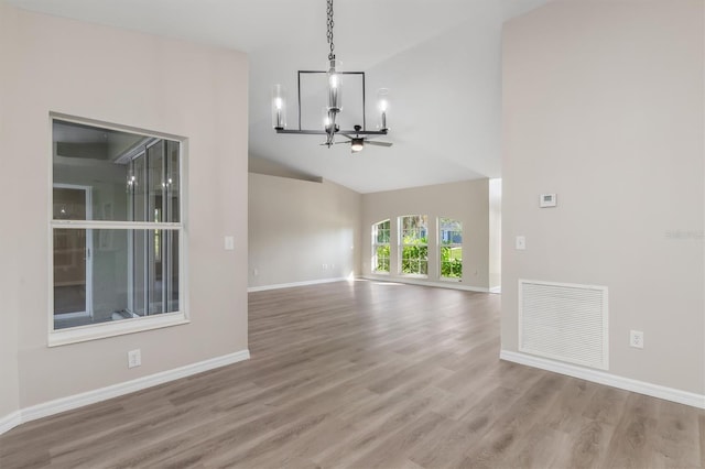 2381 Sheila Ln, North Port, FL 34286 - unfurnished living room with a chandelier, wood finished floors, high vaulted ceiling, and baseboards