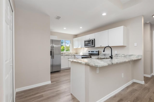 2381 Sheila Ln, North Port, FL 34286 - kitchen featuring stainless steel appliances, a peninsula, light stone counters, baseboards, and light wood-style flooring