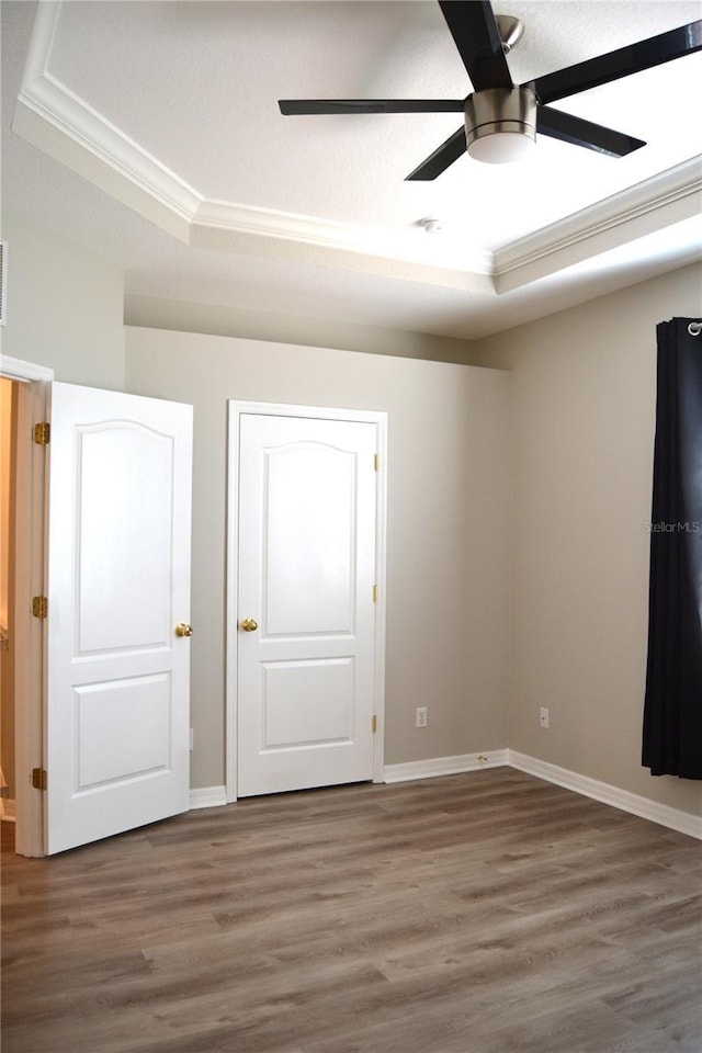 1271 Jonah Dr, North Port, FL 34289 - unfurnished bedroom with crown molding, a tray ceiling, wood finished floors, and a ceiling fan