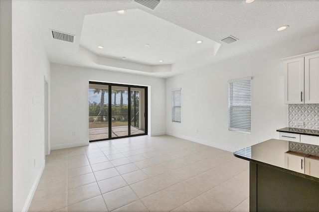 281 Potenza Loop, Nokomis, FL 34275 - unfurnished living room featuring baseboards, a tray ceiling, recessed lighting, light tile patterned flooring, and a textured ceiling