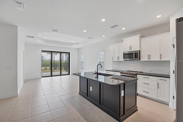281 Potenza Loop, Nokomis, FL 34275 - kitchen featuring stainless steel appliances, a sink, dark countertops, tasteful backsplash, and an island with sink
