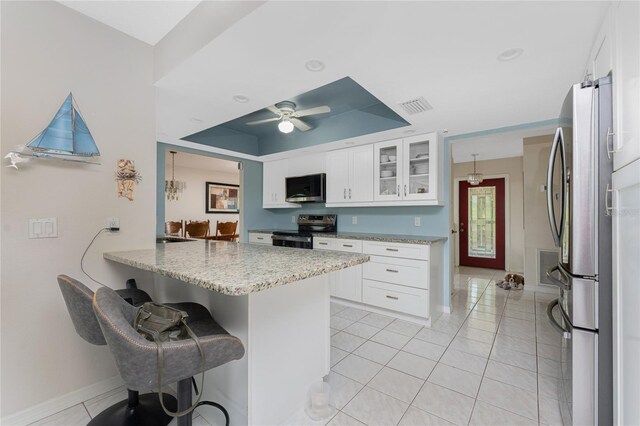 2008 Pellam Blvd, Port Charlotte, FL 33948 - kitchen with stainless steel appliances, a tray ceiling, a breakfast bar area, white cabinets, and light stone counters