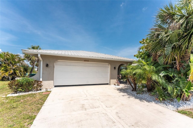 2008 Pellam Blvd, Port Charlotte, FL 33948 - view of front facade with stucco siding, concrete driveway, a garage, and metal roof