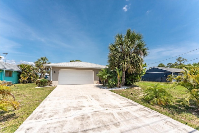 2008 Pellam Blvd, Port Charlotte, FL 33948 - view of front of house with stucco siding, a front lawn, driveway, a garage, and metal roof