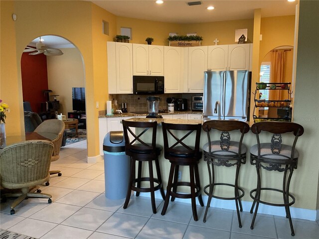 1961 Palo Duro Blvd, North Fort Myers, FL 33917 - kitchen featuring black microwave, freestanding refrigerator, arched walkways, decorative backsplash, and a kitchen bar