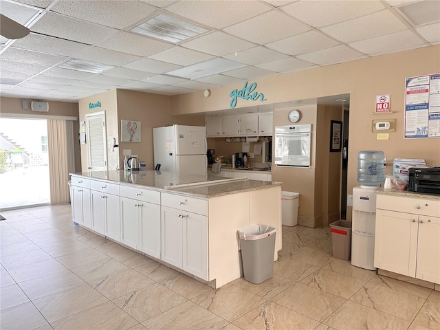 4158 Tamiami Trl Unit A5, Port Charlotte, FL 33952 - kitchen with white appliances, a center island, a paneled ceiling, white cabinetry, and light marble finish floors