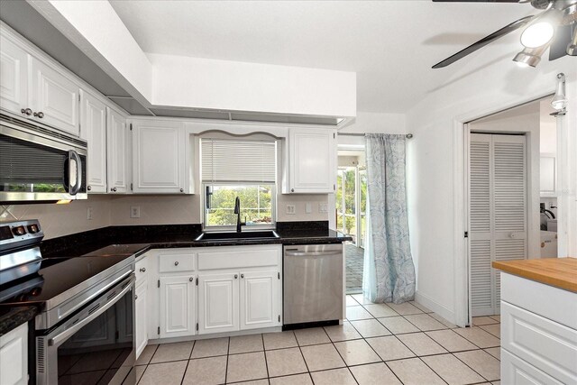 25449 Doredo Dr, Punta Gorda, FL 33955 - kitchen with stainless steel appliances, a sink, a ceiling fan, light tile patterned floors, and white cabinetry