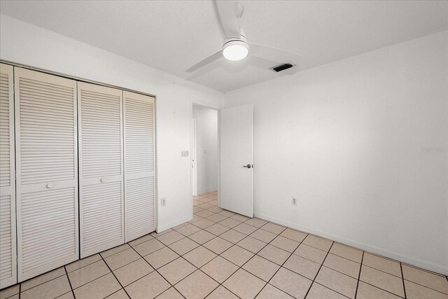 25449 Doredo Dr, Punta Gorda, FL 33955 - unfurnished bedroom with a closet, a ceiling fan, baseboards, and light tile patterned floors
