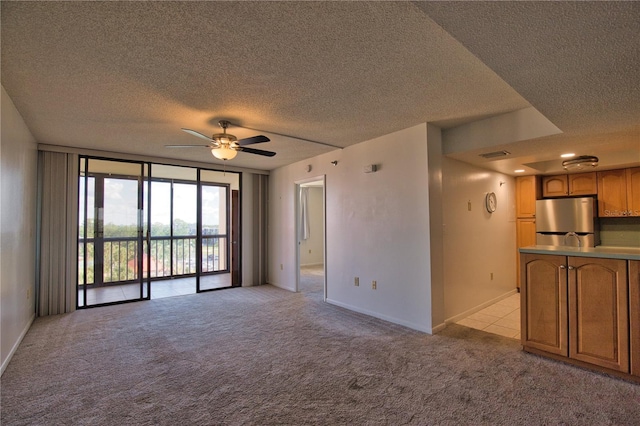 3006 Caring Way Unit 615, Port Charlotte, FL 33952 - unfurnished living room with light carpet, a textured ceiling, ceiling fan, baseboards, and floor to ceiling windows
