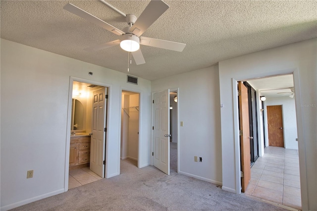 3006 Caring Way Unit 615, Port Charlotte, FL 33952 - unfurnished bedroom featuring carpet, a walk in closet, a textured ceiling, ensuite bathroom, and a closet