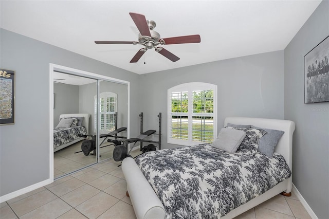 bedroom with baseboards, light tile patterned floors, a closet, and ceiling fan