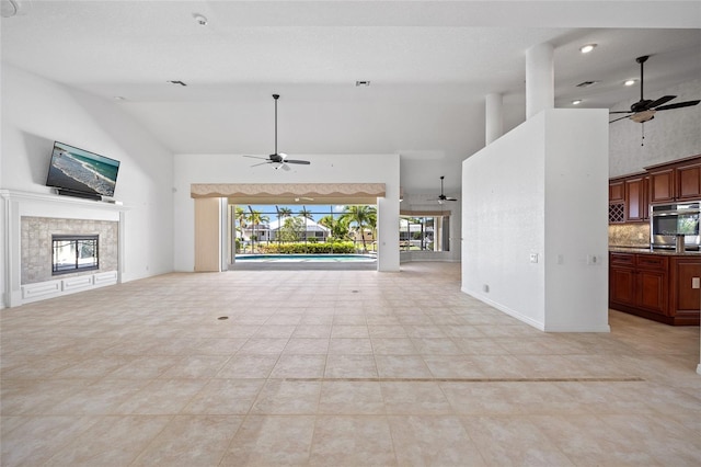 2719 Mayaguana Ct, Punta Gorda, FL 33950 - unfurnished living room featuring a ceiling fan, high vaulted ceiling, a fireplace, and light tile patterned floors