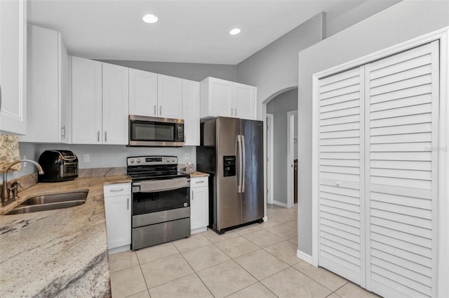 kitchen featuring stainless steel appliances, a sink, white cabinets, arched walkways, and recessed lighting