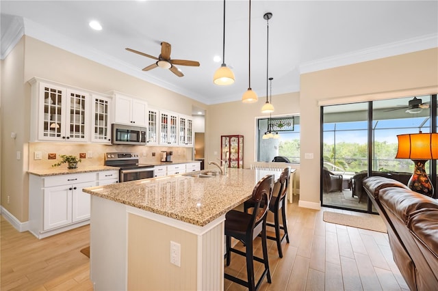 19246 Moore Haven Ct, Port Charlotte, FL 33948 - kitchen featuring appliances with stainless steel finishes, ceiling fan, light wood finished floors, a breakfast bar area, and ornamental molding