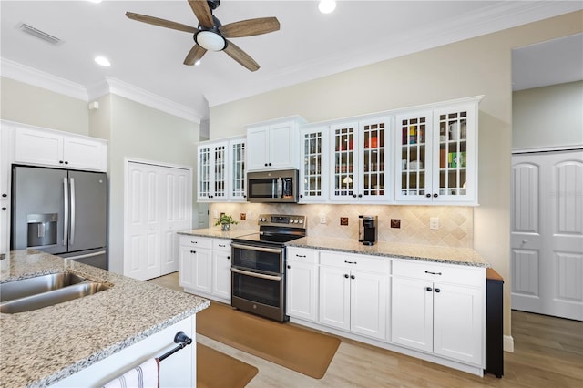 19246 Moore Haven Ct, Port Charlotte, FL 33948 - kitchen featuring appliances with stainless steel finishes, crown molding, ceiling fan, backsplash, and white cabinets
