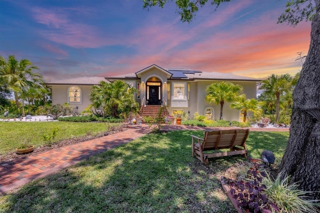 6242 Tropicaire Blvd, North Port, FL 34291 - view of front of house with stucco siding, a front yard, and roof mounted solar panels