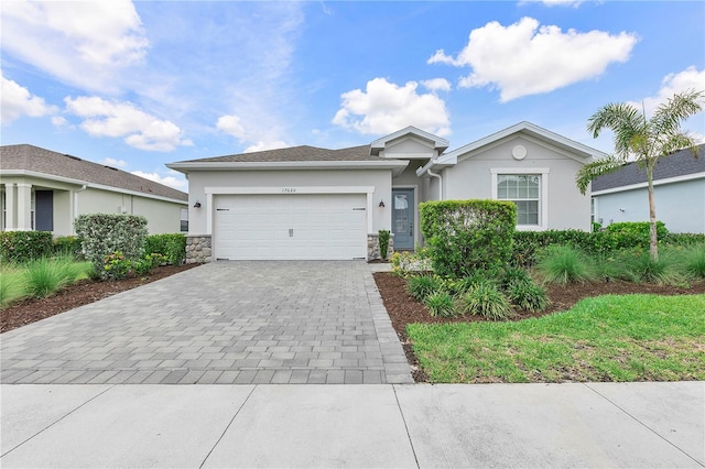 17620 Winding Wood Ln, Punta Gorda, FL 33982 - ranch-style home featuring stucco siding, decorative driveway, a garage, and stone siding
