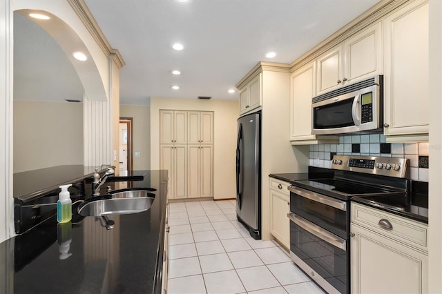 485 Dorchester St, Port Charlotte, FL 33954 - kitchen with cream cabinets, stainless steel appliances, dark countertops, a sink, and arched walkways