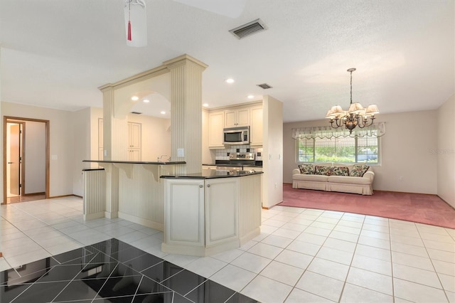 485 Dorchester St, Port Charlotte, FL 33954 - kitchen featuring appliances with stainless steel finishes, dark countertops, cream cabinets, open floor plan, and a chandelier