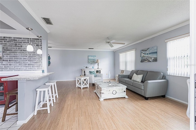 living area featuring ceiling fan, crown molding, wood finished floors, baseboards, and a textured ceiling