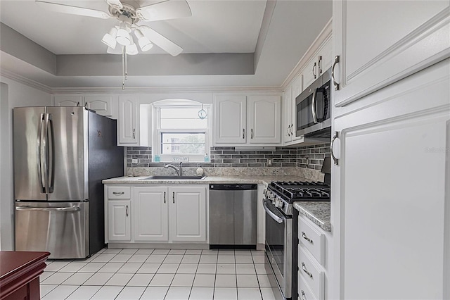 kitchen featuring stainless steel appliances, a sink, ceiling fan, and white cabinetry