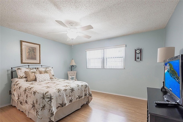 bedroom featuring light wood-style flooring, a textured ceiling, ceiling fan, and baseboards