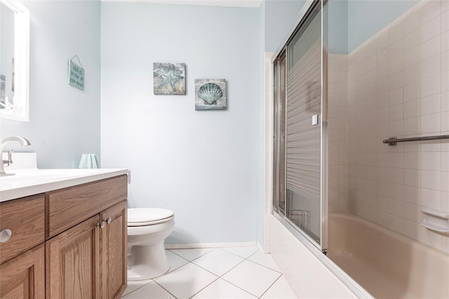 bathroom featuring tile patterned floors, toilet, vanity, enclosed tub / shower combo, and baseboards