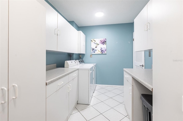 clothes washing area with washer and dryer, cabinet space, light tile patterned floors, and baseboards