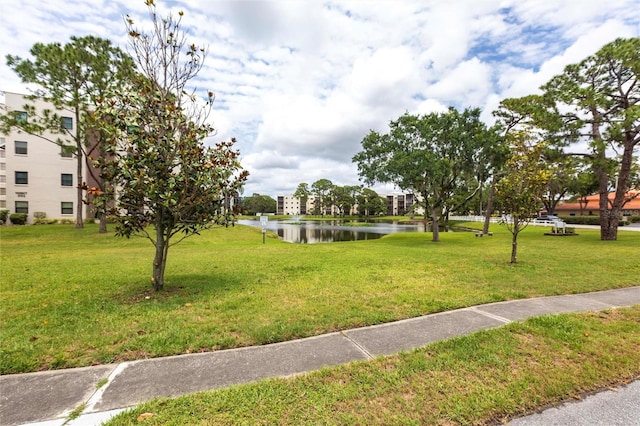 surrounding community with a water view and a lawn
